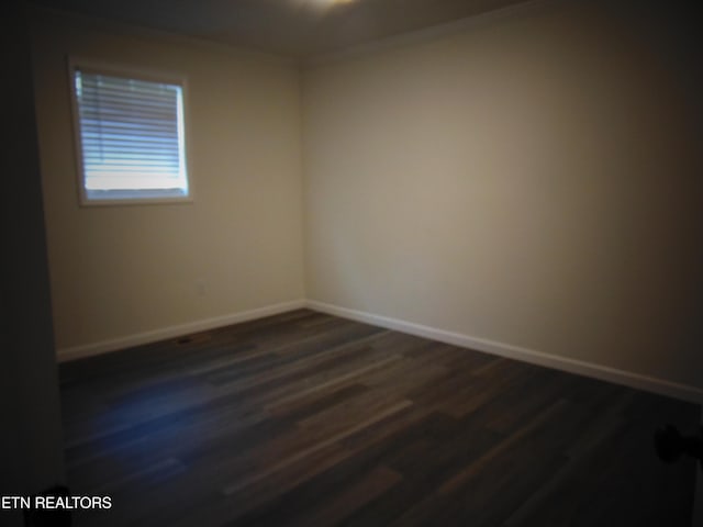 empty room featuring crown molding and dark hardwood / wood-style flooring