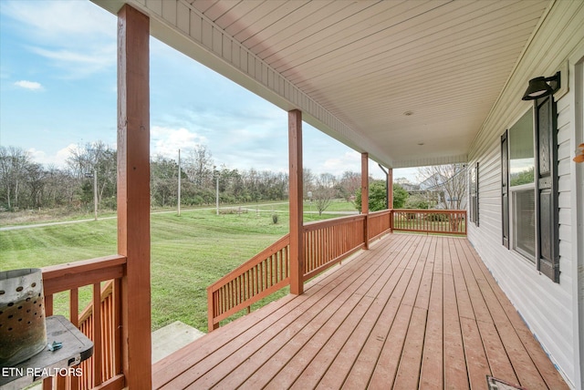 wooden terrace featuring covered porch and a yard