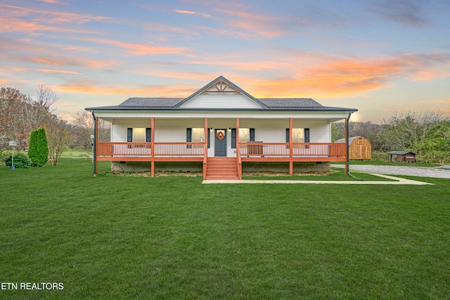 farmhouse with a lawn, a storage shed, and covered porch