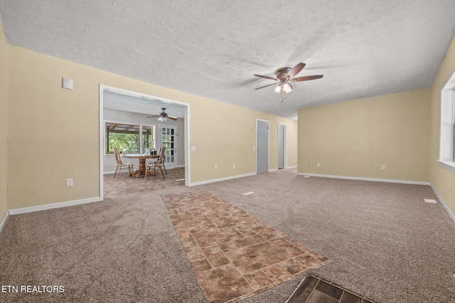 unfurnished living room featuring carpet flooring, a textured ceiling, and ceiling fan