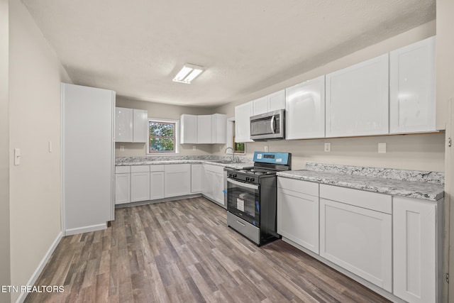 kitchen featuring wood-type flooring, white cabinetry, sink, and appliances with stainless steel finishes