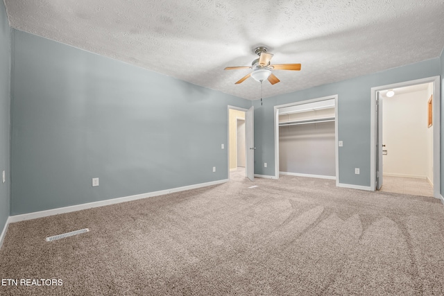 unfurnished bedroom with carpet, ceiling fan, a textured ceiling, and a closet