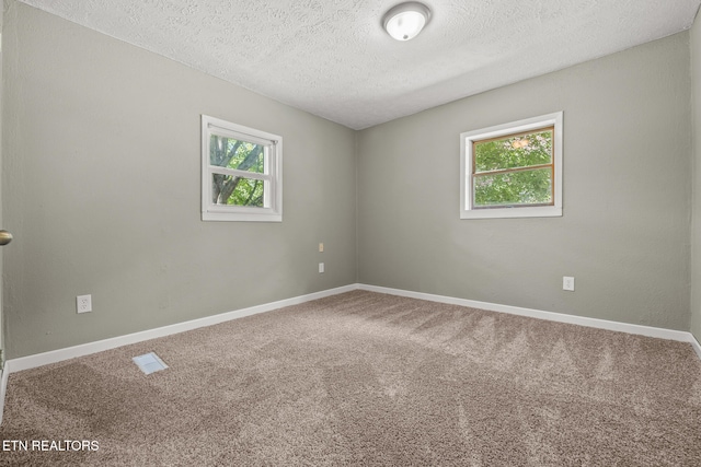 carpeted empty room featuring a textured ceiling