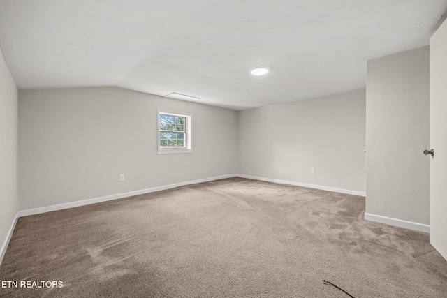 spare room featuring carpet flooring and lofted ceiling