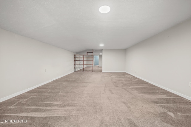 unfurnished room with a textured ceiling, carpet floors, and lofted ceiling