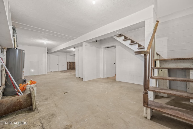 basement featuring water heater and a textured ceiling