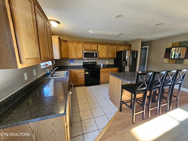 kitchen featuring sink, a kitchen island, a breakfast bar, light tile patterned floors, and appliances with stainless steel finishes