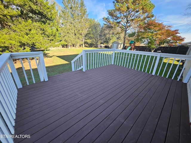 wooden deck featuring a playground, a yard, and a shed