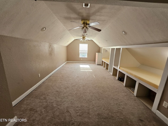 bonus room featuring carpet, a textured ceiling, vaulted ceiling, and ceiling fan