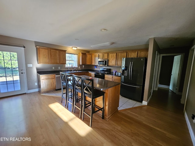 kitchen featuring a center island, sink, light hardwood / wood-style flooring, appliances with stainless steel finishes, and a breakfast bar area