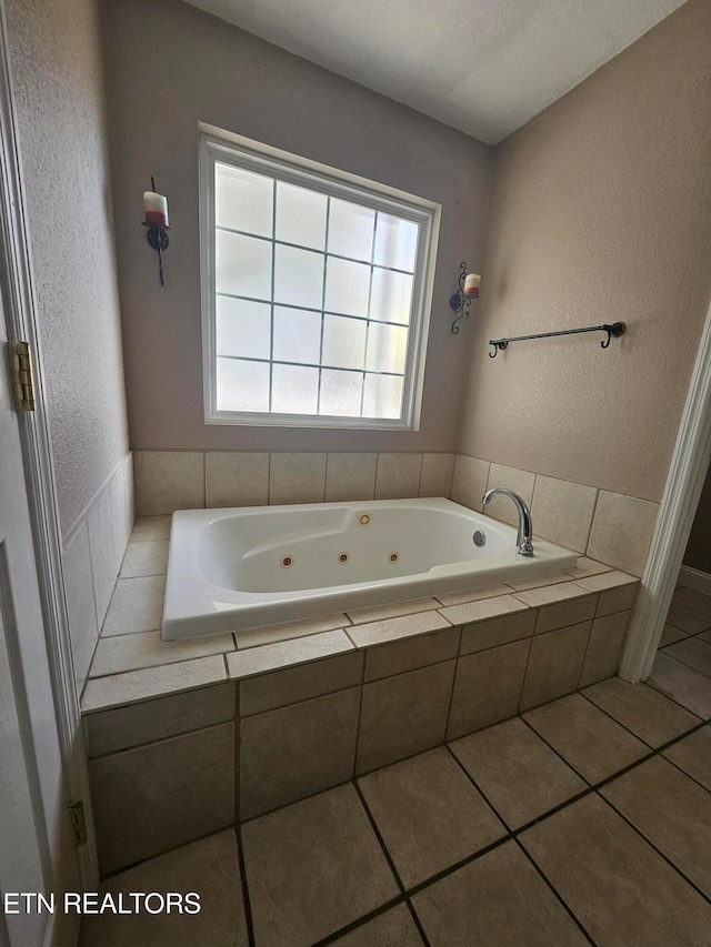 bathroom with tiled tub and tile patterned flooring