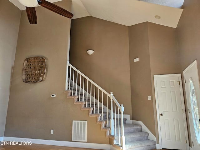 stairway with hardwood / wood-style flooring, ceiling fan, and lofted ceiling