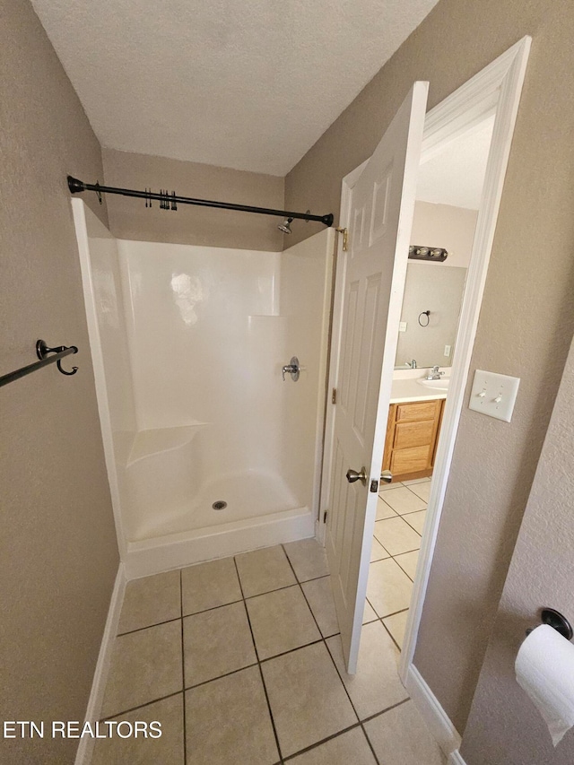 bathroom featuring tile patterned floors, a shower, vanity, and a textured ceiling