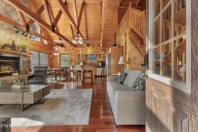 living room featuring wooden walls, dark hardwood / wood-style floors, a fireplace, beamed ceiling, and wood ceiling