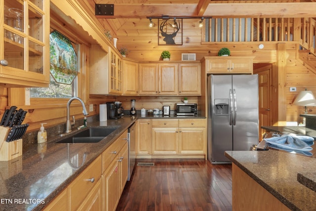 kitchen featuring appliances with stainless steel finishes, dark wood-type flooring, wooden walls, and sink