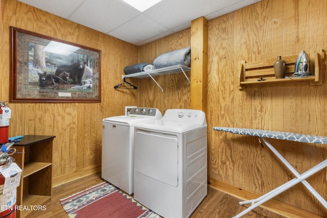 clothes washing area with hardwood / wood-style flooring, washer and dryer, and wooden walls