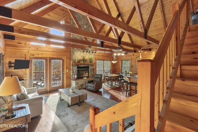 living room featuring wood ceiling, beam ceiling, hardwood / wood-style flooring, a stone fireplace, and wood walls