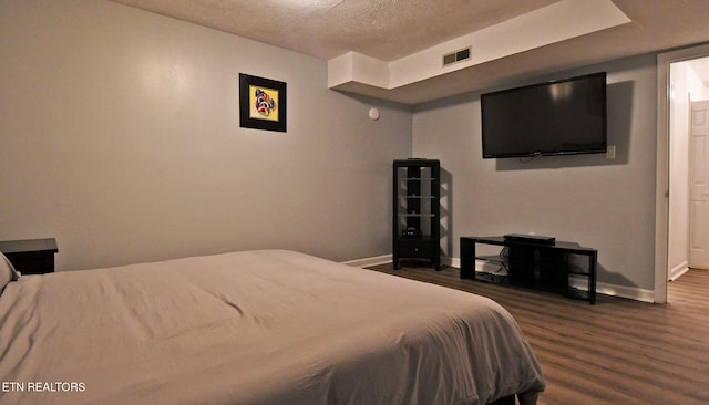 bedroom featuring dark hardwood / wood-style flooring and a textured ceiling