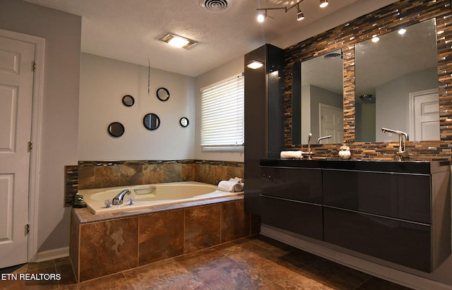 bathroom featuring a relaxing tiled tub, a textured ceiling, and vanity