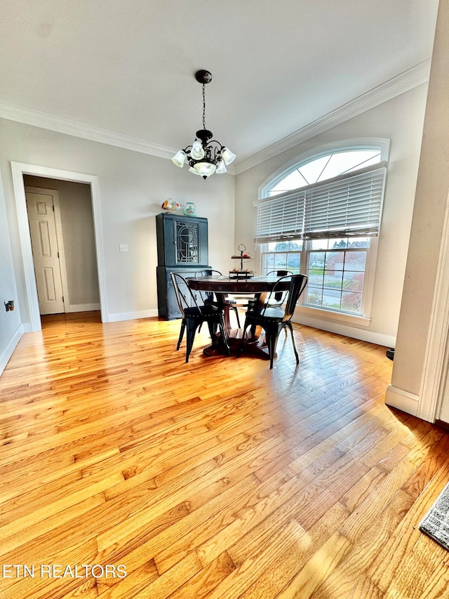 dining area with crown molding, light wood-type flooring, and a notable chandelier