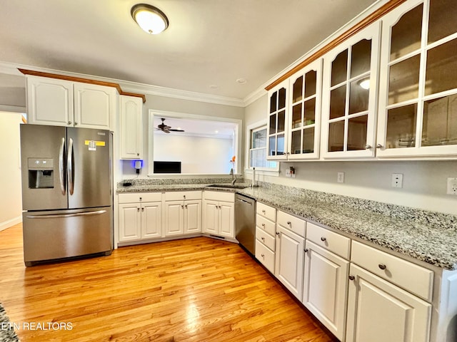 kitchen featuring appliances with stainless steel finishes, light wood-type flooring, ornamental molding, sink, and white cabinetry