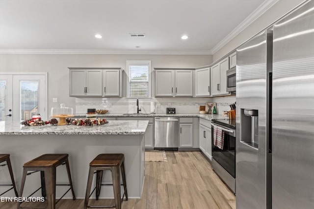 kitchen featuring light stone counters, plenty of natural light, light wood-type flooring, and appliances with stainless steel finishes