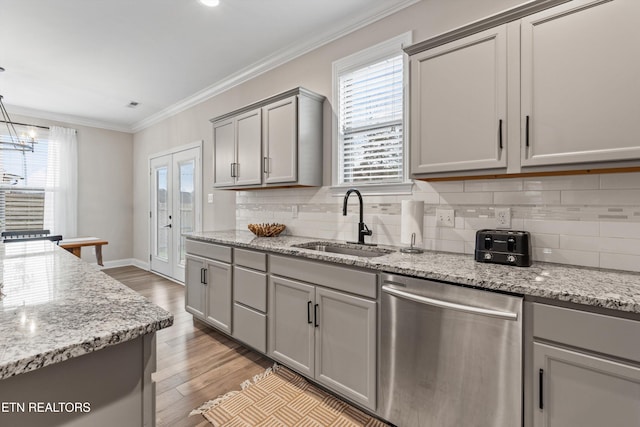 kitchen featuring pendant lighting, dishwasher, sink, ornamental molding, and light hardwood / wood-style floors