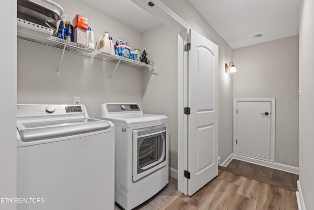 laundry room featuring separate washer and dryer and light hardwood / wood-style flooring