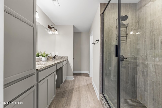 bathroom with wood-type flooring, vanity, and an enclosed shower