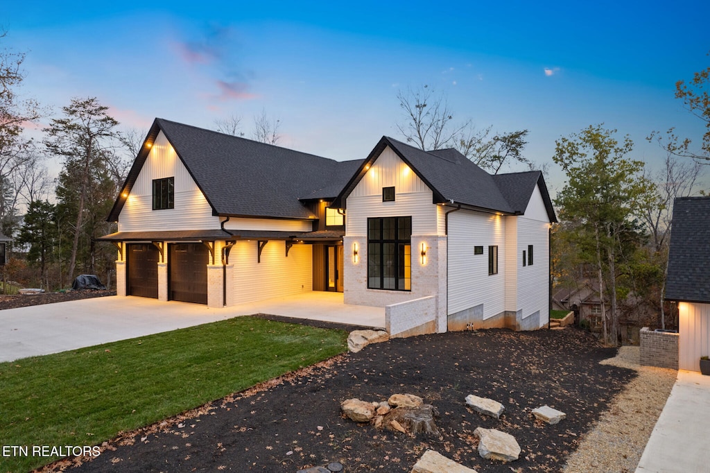 modern inspired farmhouse featuring a garage and a lawn