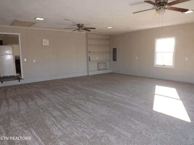 empty room with electric panel, carpet, attic access, and a ceiling fan