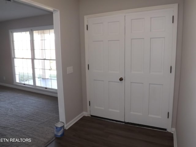 entryway with dark wood-type flooring, baseboards, and dark colored carpet