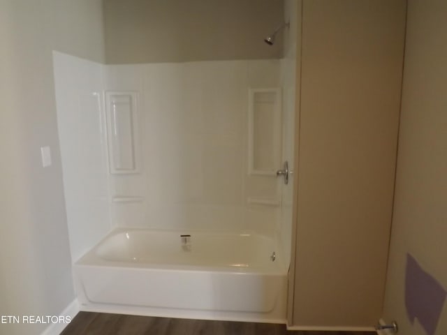bathroom featuring wood finished floors and washtub / shower combination