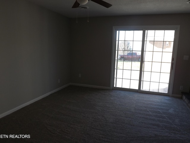unfurnished room featuring baseboards, a ceiling fan, and dark colored carpet