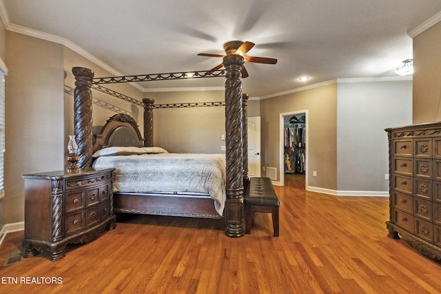 bedroom with ceiling fan, crown molding, hardwood / wood-style flooring, a spacious closet, and a closet