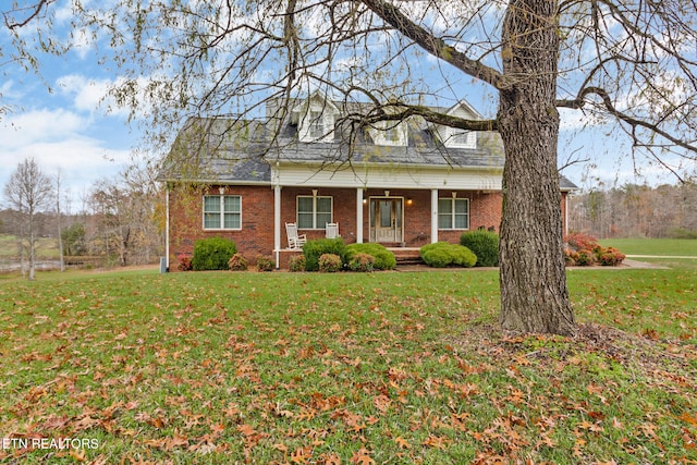 cape cod-style house with a front yard and covered porch