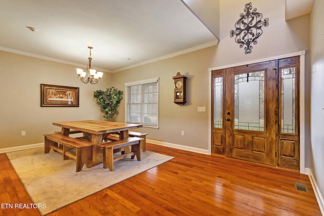 dining room with wood-type flooring, ornamental molding, and a chandelier