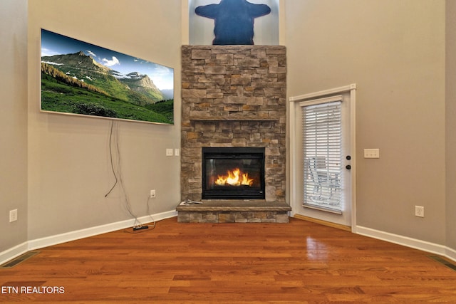 unfurnished living room featuring a stone fireplace and wood-type flooring