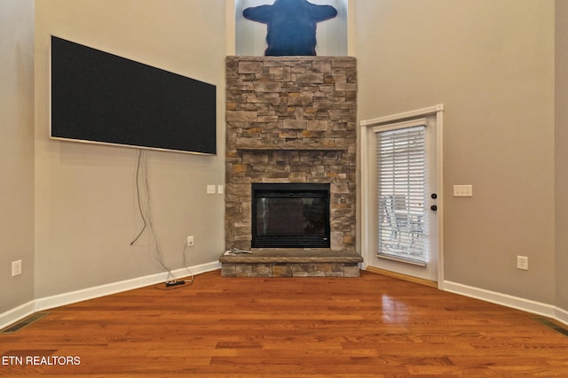 unfurnished living room with a stone fireplace and wood-type flooring