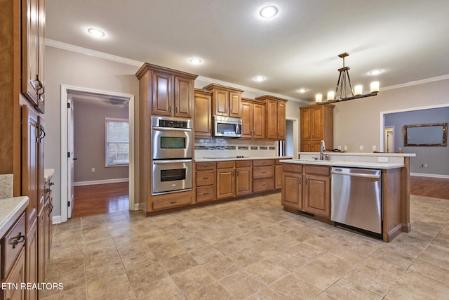 kitchen with a kitchen island with sink, crown molding, hanging light fixtures, appliances with stainless steel finishes, and a chandelier