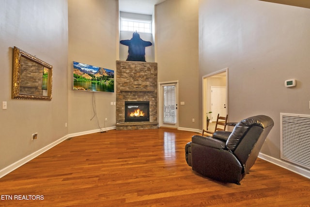 living room featuring a fireplace, hardwood / wood-style floors, and a high ceiling