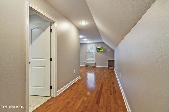 bonus room featuring light wood-type flooring, an AC wall unit, and lofted ceiling