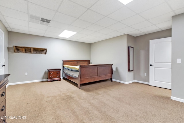 bedroom with a drop ceiling and light carpet