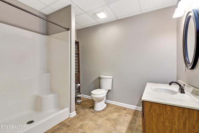 bathroom featuring a drop ceiling, vanity, a shower, tile patterned flooring, and toilet