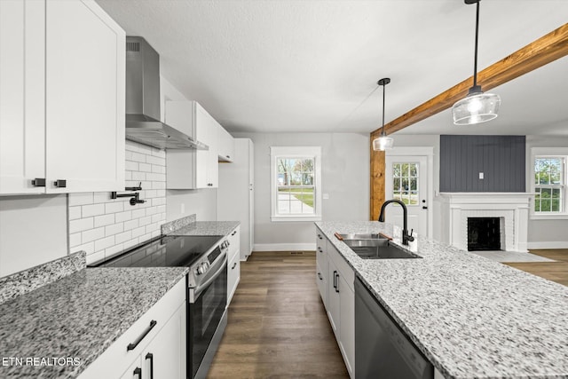 kitchen with white cabinets, appliances with stainless steel finishes, sink, and wall chimney range hood