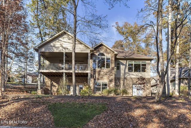 view of front facade with stone siding, a ceiling fan, and a balcony