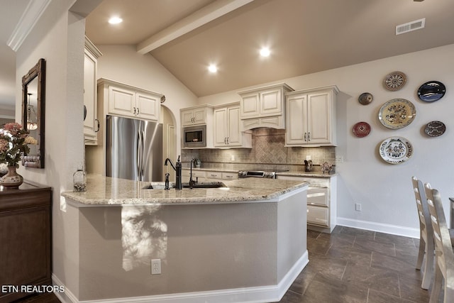 kitchen featuring light stone counters, backsplash, stainless steel appliances, and kitchen peninsula