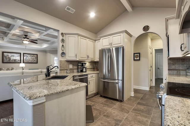 kitchen featuring sink, appliances with stainless steel finishes, light stone countertops, kitchen peninsula, and beamed ceiling