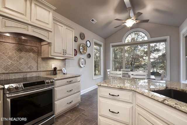 kitchen with stainless steel range with electric cooktop, vaulted ceiling, custom range hood, cream cabinets, and decorative backsplash