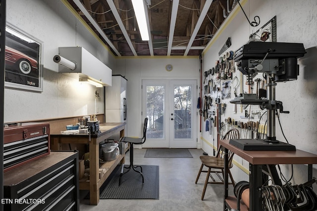 office area with french doors, a workshop area, and concrete floors